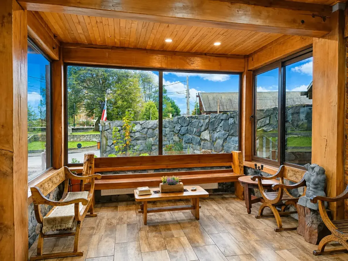 Sala de estar revestida en madera con grandes ventanales y vista hacia el jardín
